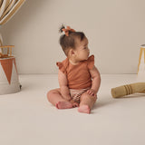 Baby with a hair bow sitting in the Rylee & Cru Flutter Sleeve Bodysuit in Poppy with striped bloomers