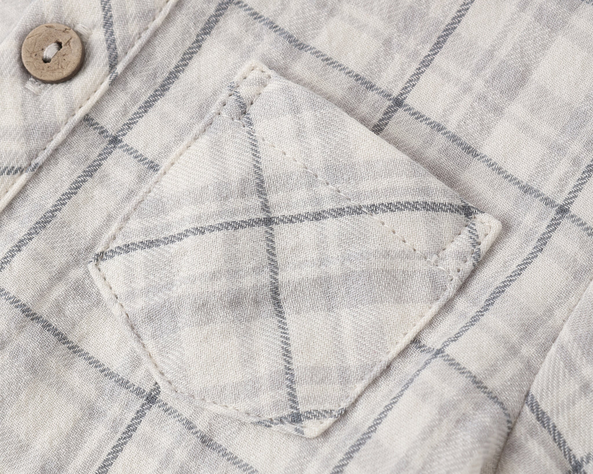 Close-up of the chest pocket and wooden button on the Rylee & Cru Jaxson Shirt in Blue Plaid