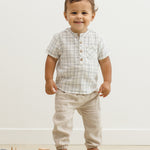 Smiling toddler facing forward in the Rylee & Cru Jaxson Shirt in Blue Plaid and tan pants