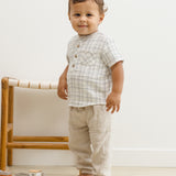 Toddler standing beside a rattan chair in the Rylee & Cru Jaxson Shirt in Blue Plaid and tan pants