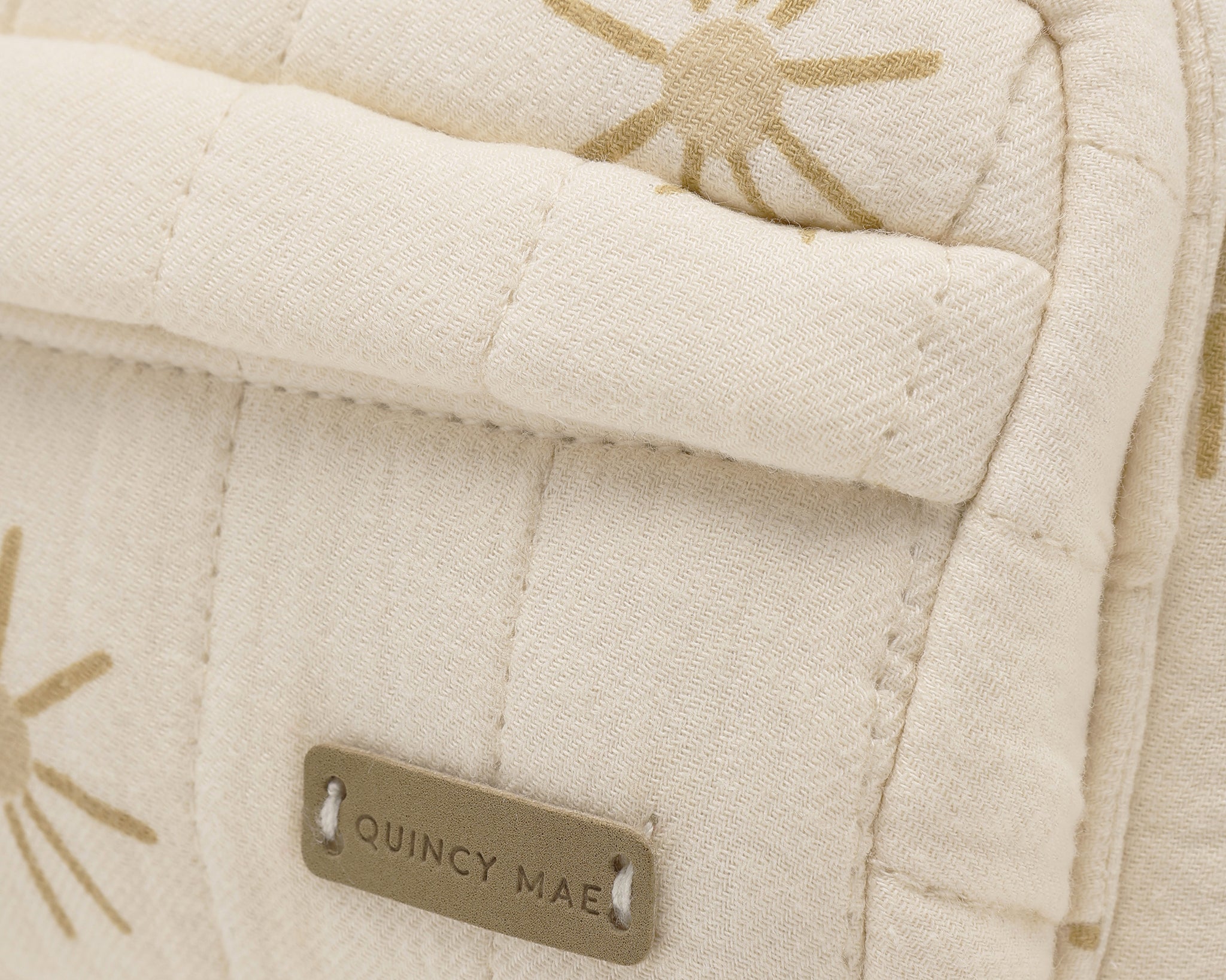 Rylee & Cru Mini Backpack in Sunburst, close-up of the gold sun print and Quincy Mae label