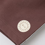Close-up of the R+C sun logo patch on the Rylee & Cru Paneled Boardshort in Chocolate