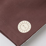 Close-up of the R+C sun logo patch on the Rylee & Cru Paneled Boardshort in Chocolate