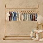 Rylee & Cru swim collection on a wooden rack with toy life rings, Paneled Boardshorts included