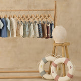 Rylee & Cru swim collection hanging on a wooden rack with a toy life ring, Paneled Boardshorts included