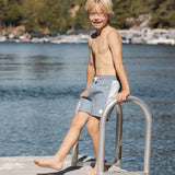 Boy on a lake dock ladder wearing the Rylee & Cru Paneled Boardshort in Marine