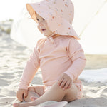Baby in a sun bonnet playing on the beach in the Rylee & Cru Rashguard Long Sleeve in Blush