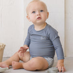 Baby sitting in the Rylee & Cru Rashguard Long Sleeve in Ocean with gingham swim trunks