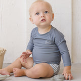 Baby sitting in the Rylee & Cru Rashguard Long Sleeve in Ocean with gingham swim trunks