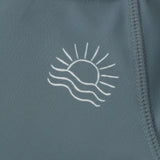 Close-up of the embroidered sun and wave logo on the Rylee & Cru Rashguard Long Sleeve in Ocean