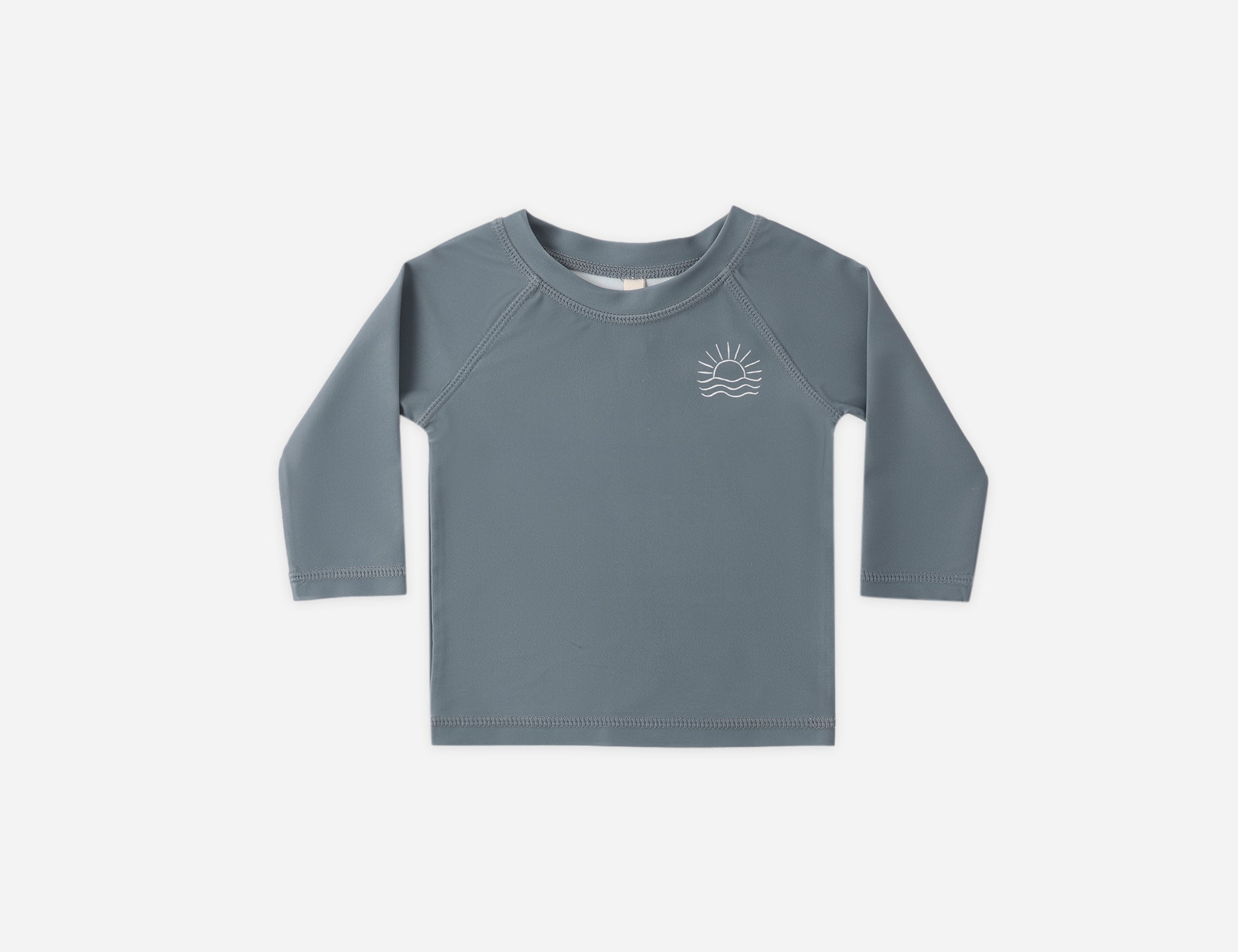 Rylee & Cru Rashguard Long Sleeve in Ocean, a slate blue baby swim top with a small sun logo, laid flat