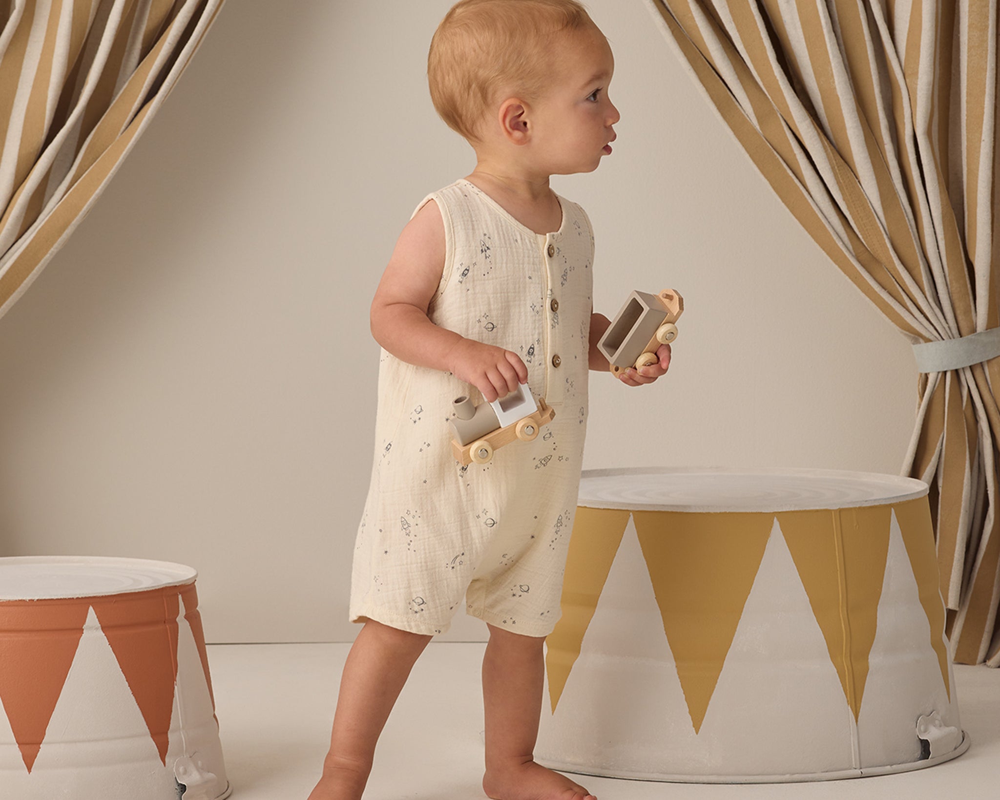 Toddler walking past striped drums wearing the Rylee & Cru Romper in Space