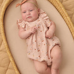 Baby with a bow headband lying in a wicker bassinet wearing the Rylee & Cru Ruffle Romper in Cherries