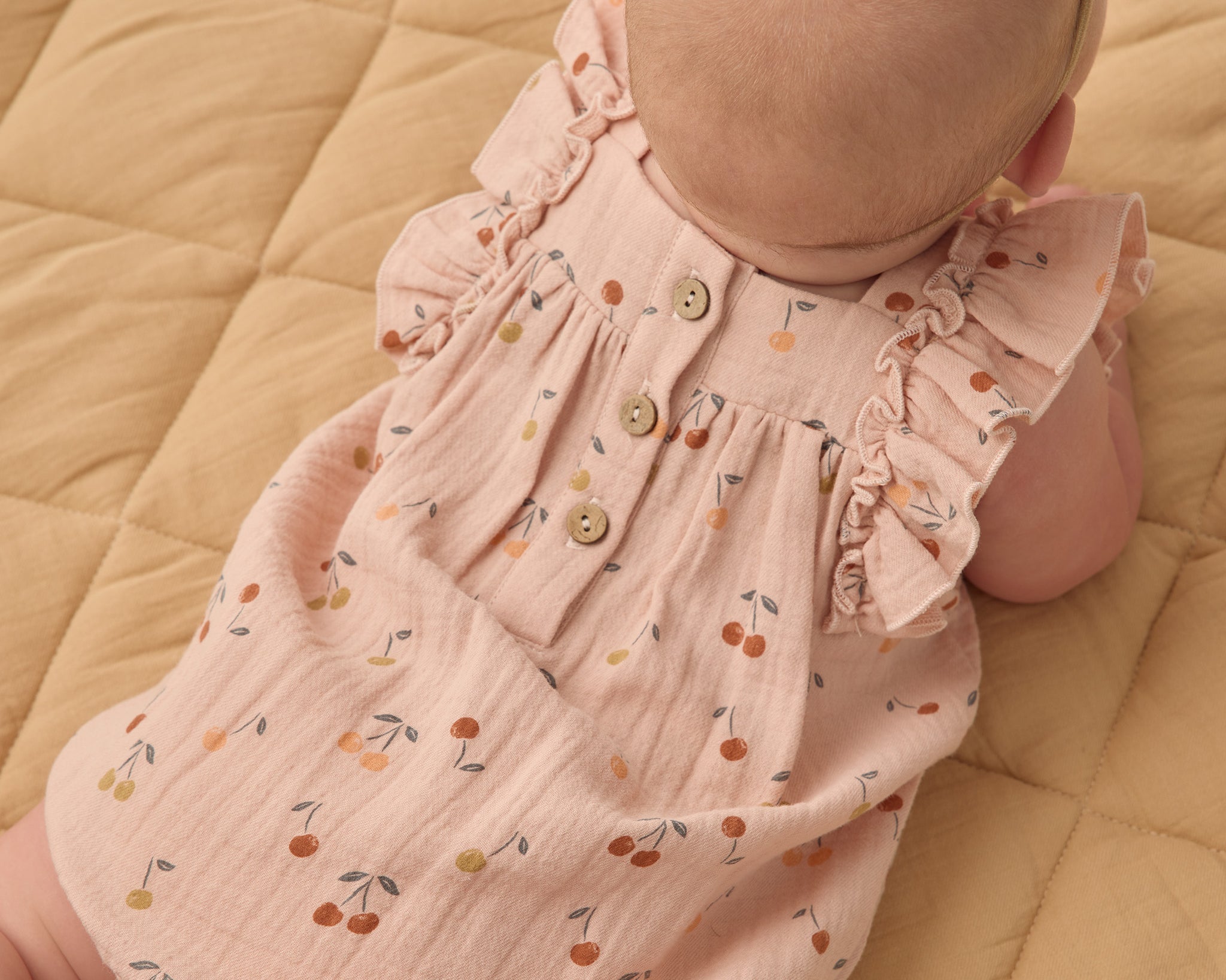 Back view of the Rylee & Cru Ruffle Romper in Cherries showing the wooden button closure