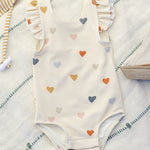 Rylee & Cru Scoop Back One-Piece Swimsuit in Confetti Hearts on a striped towel, angled view