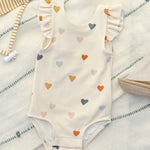 Rylee & Cru Scoop Back One-Piece Swimsuit in Confetti Hearts laid on a striped towel