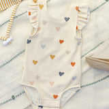 Rylee & Cru Scoop Back One-Piece Swimsuit in Confetti Hearts laid on a striped towel