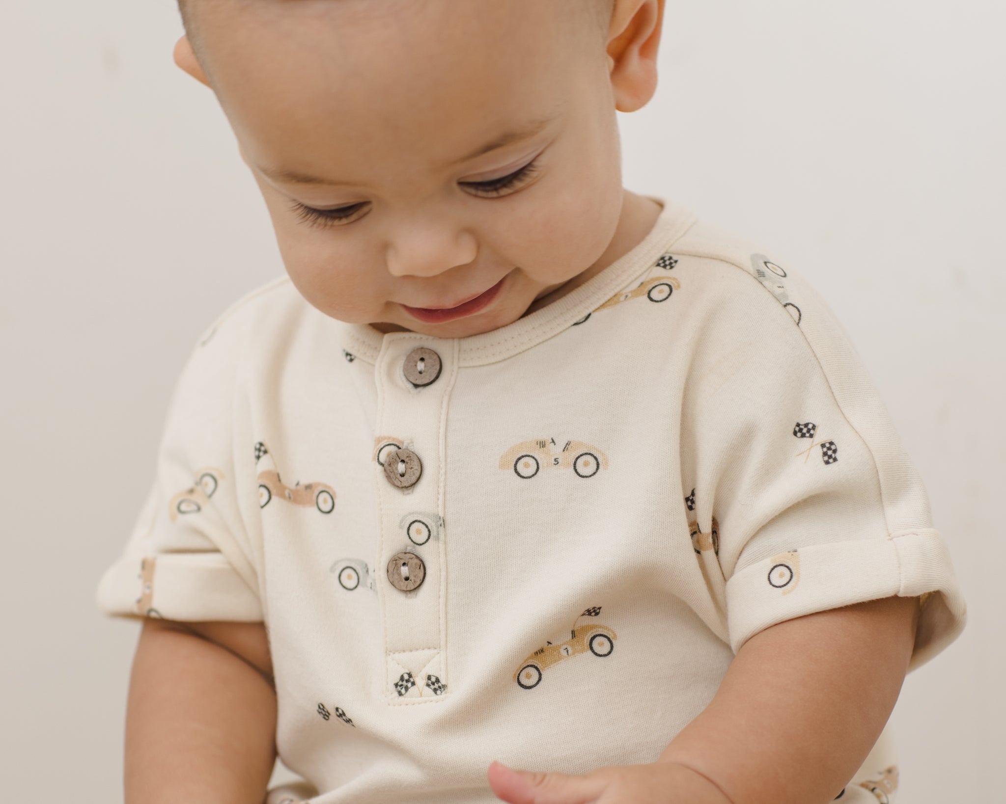 Baby looking down while wearing the Rylee & Cru Short Sleeve One-Piece in Race Car