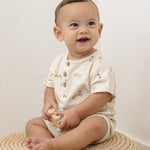 Smiling baby sitting on a jute rug wearing the Rylee & Cru Short Sleeve One-Piece in Race Car