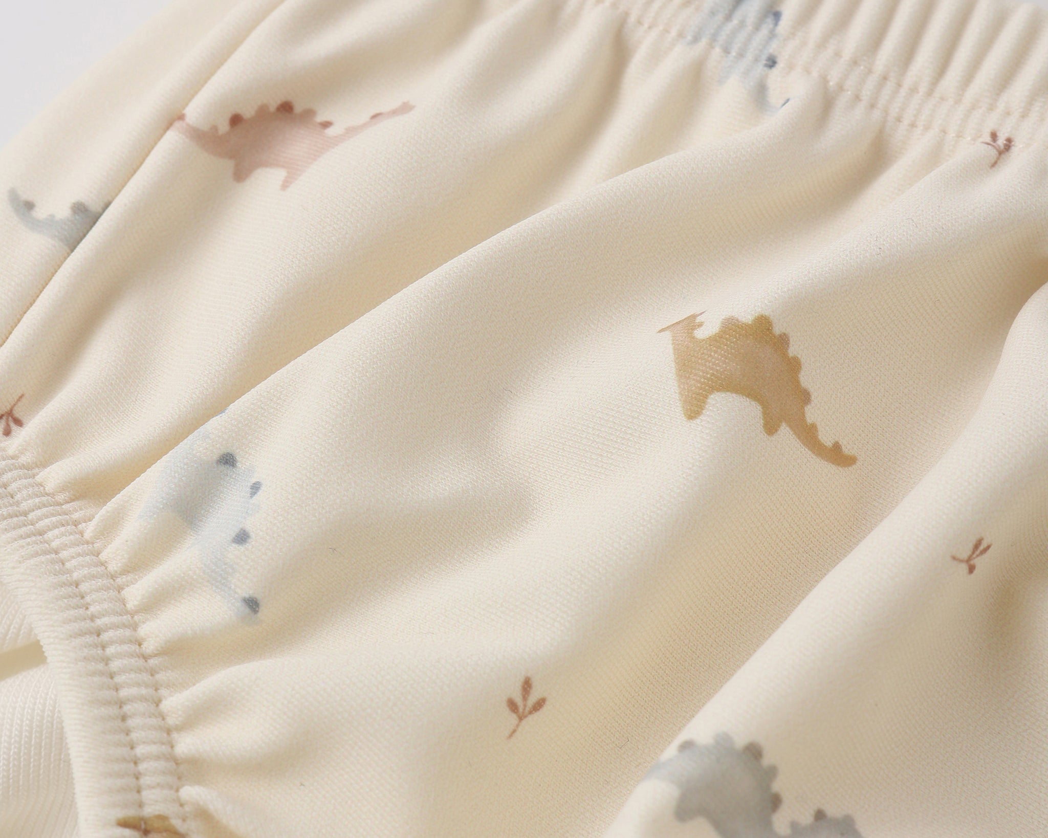 Close-up of the pastel dinosaur print and elastic waistband on the Rylee & Cru Swim Diaper in Dino