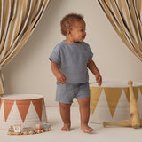 Toddler in a blue gauze set walking past striped drums wearing the Rylee & Cru Utility Short in Ocean