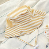 Rylee & Cru Youth Bucket Hat in Honey Stripe laid on a striped blanket