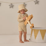 Toddler wearing the Rylee & Cru Youth Bucket Hat in Honey Stripe with a matching set, holding a wooden airplane