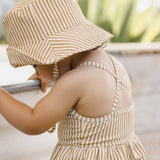 Toddler wearing the Rylee & Cru Youth Bucket Hat in Honey Stripe outdoors by a pool