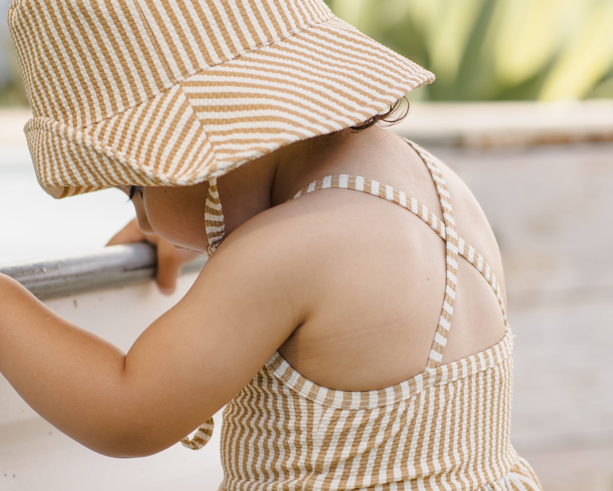 Toddler wearing the Rylee & Cru Youth Bucket Hat in Honey Stripe outdoors by a pool