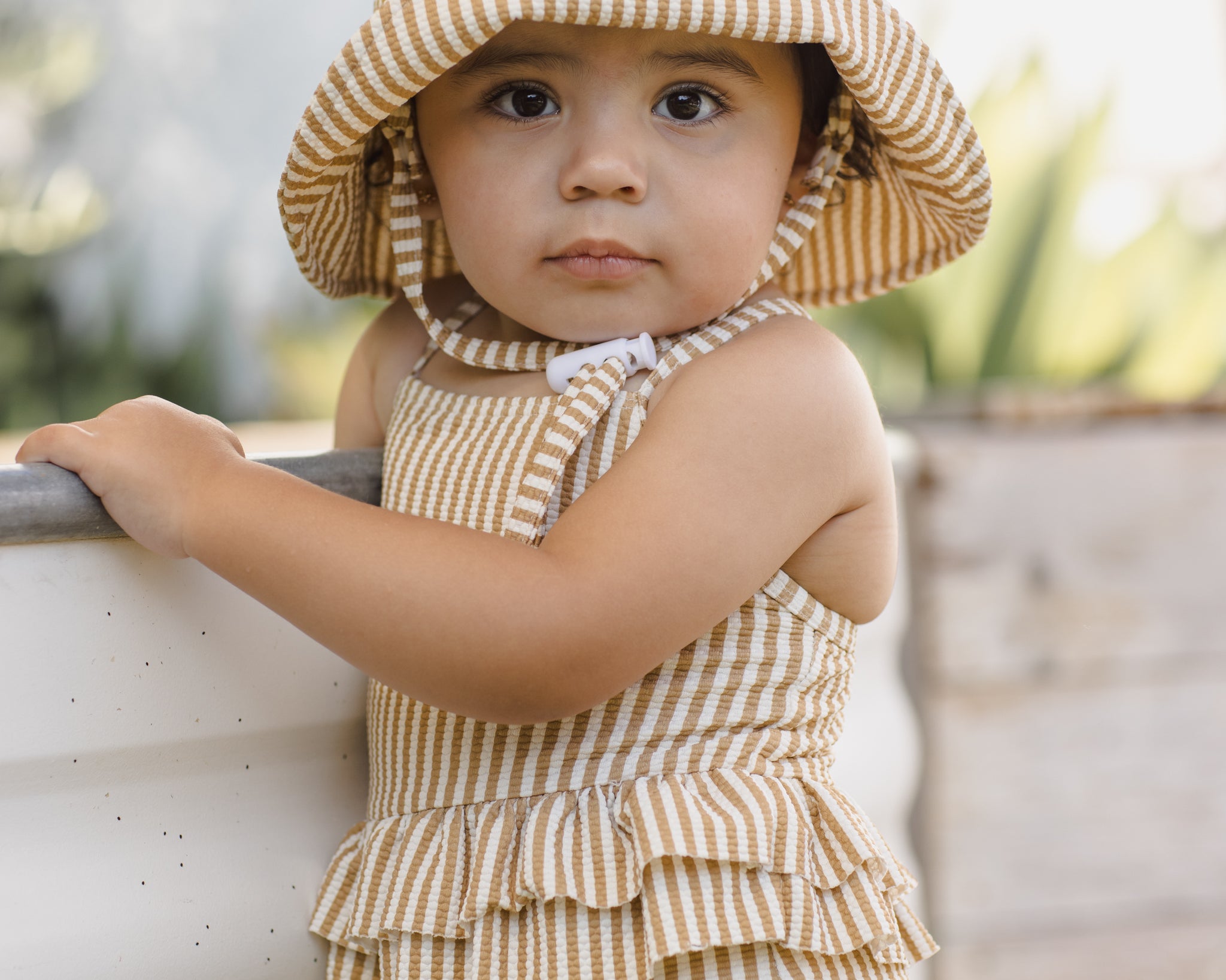 Baby wearing the Rylee & Cru Youth Bucket Hat in Marigold Stripe, front view