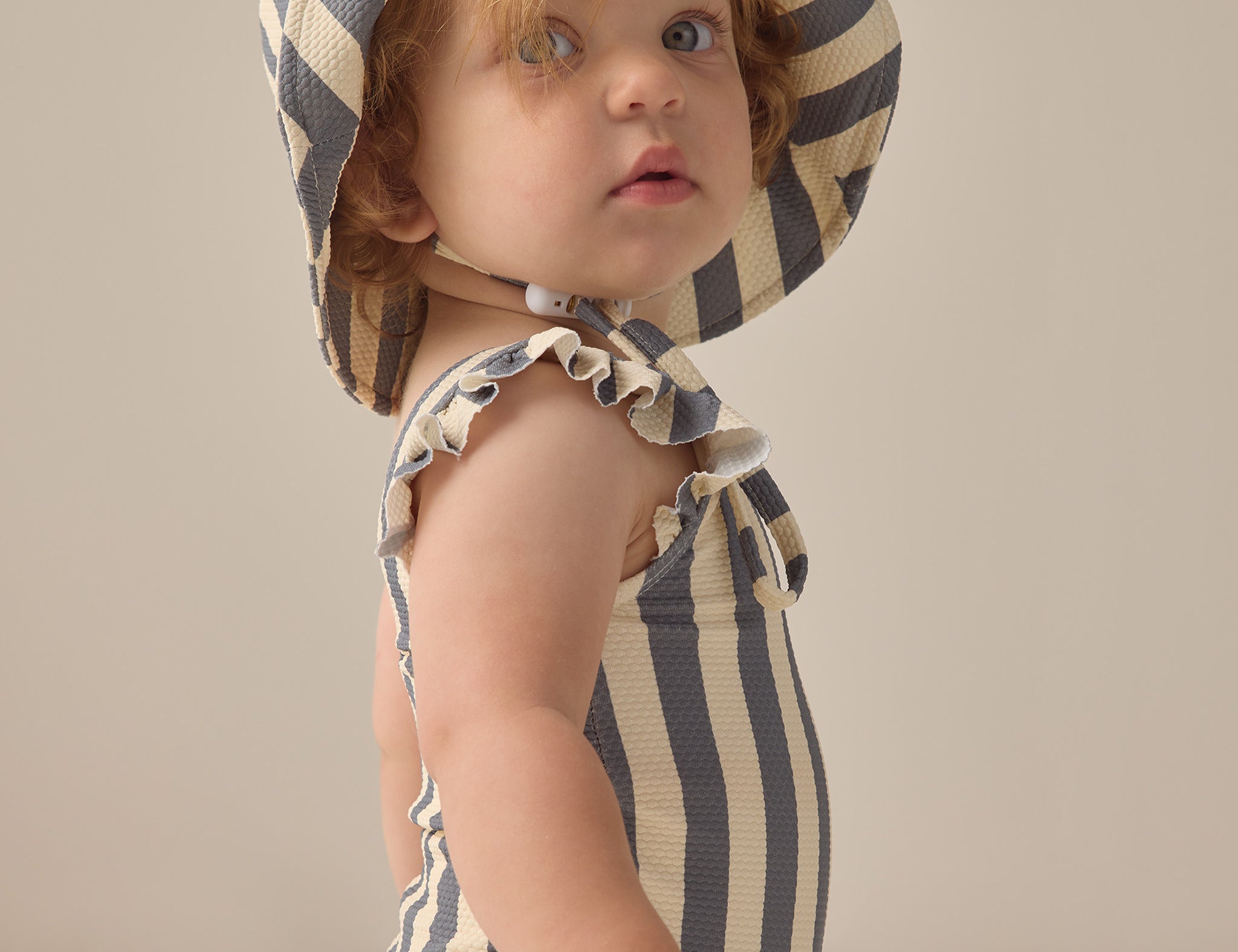 Baby wearing the Rylee & Cru Youth Bucket Hat in Marigold Stripe, side view