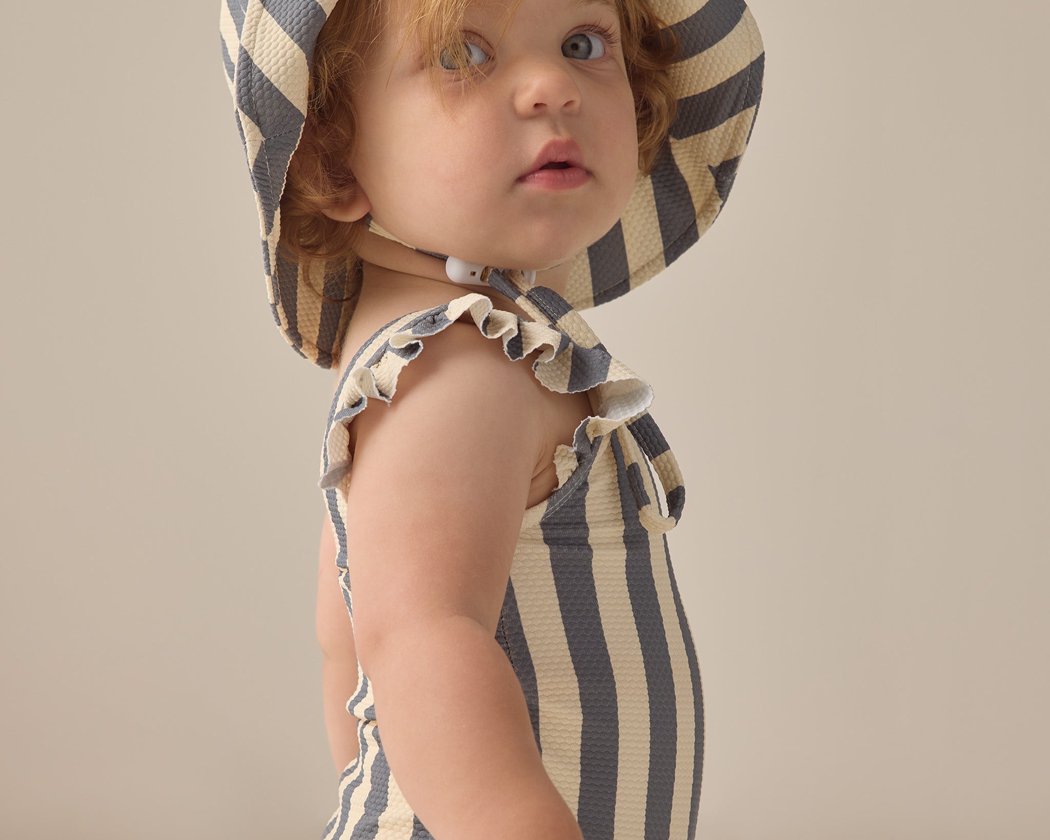 Baby wearing the Rylee & Cru Youth Bucket Hat in Marigold Stripe, side view