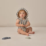 Baby sitting in a striped swimsuit wearing the Rylee & Cru Youth Bucket Hat in Retro Stripe Ocean