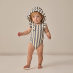 Toddler standing in a striped swimsuit wearing the Rylee & Cru Youth Bucket Hat in Retro Stripe Ocean