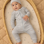 Baby in a bassinet wearing the Rylee & Cru Zip Longsleeve Sleeper in Airplane, a light blue sleeper with a matching hat