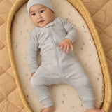 Baby in a bassinet wearing the Rylee & Cru Zip Longsleeve Sleeper in Airplane, a light blue sleeper with a matching hat