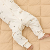 Rylee & Cru Zip Longsleeve Sleeper in Race Car laid flat on a quilt, showing the cream race car print