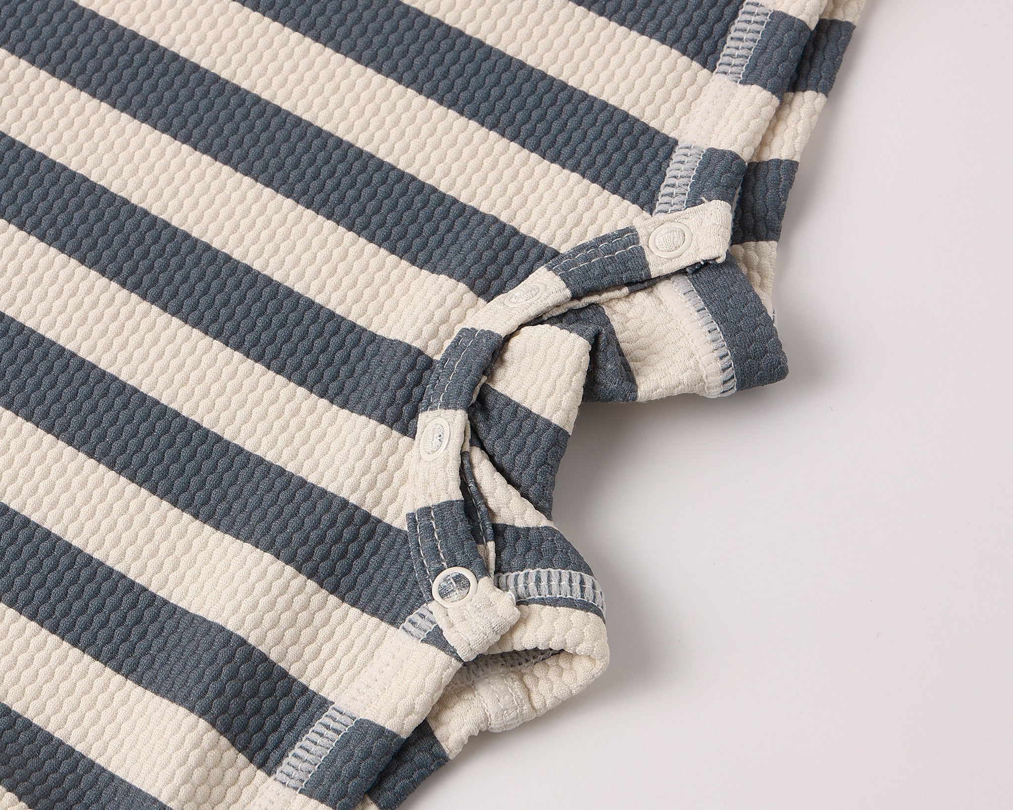 Close-up of the navy and cream textured stripe fabric on the Rylee & Cru Zip Rashguard One-Piece in Retro Ocean Stripe
