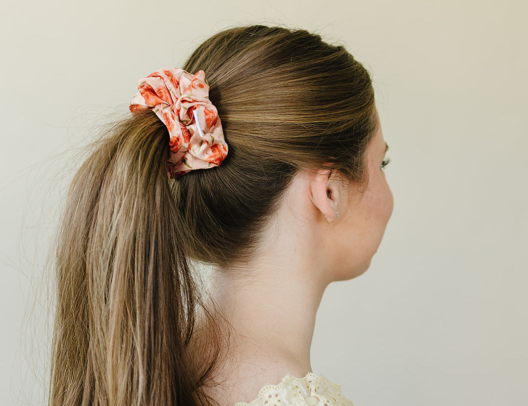 Profile view of a sleek high ponytail held with the Brushed Sand Floral satin scrunchie.