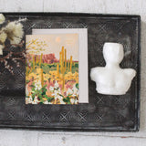 Seedlings Desert Moonlight card on a black tray with dried flowers and a small white bust