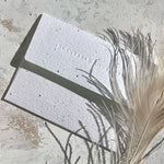 Seedlings plantable seed paper envelope with feathers and dried grass on a stone surface