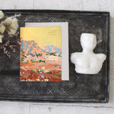 Seedlings Shadow Rocks card on a black tray with dried flowers and a small white bust