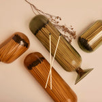 Skeem Match Cloches in amber and olive lying on their sides with dried botanicals