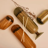 Skeem Match Cloches in amber and olive lying on their sides with dried botanicals