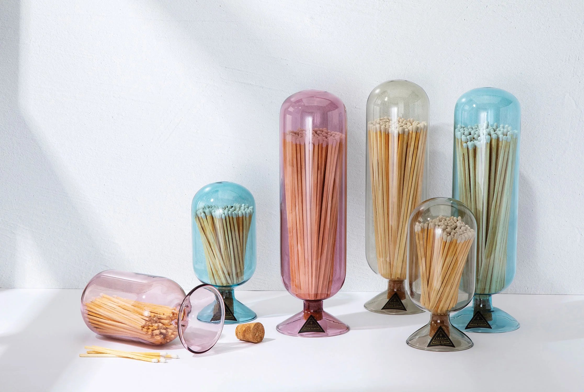 Skeem Match Cloches in aqua, plum, amber and gray standing together with loose matches