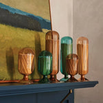 Skeem Match Cloches in assorted colors displayed on a mantel below a painting