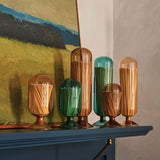 Skeem Match Cloches in assorted colors displayed on a mantel below a painting