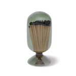 Skeem Match Cloche in Olive, a green glass dome filled with long matches on a footed base