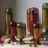 Skeem Match Cloches in olive, amber, plum and violet on a table with matches