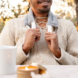 Smiling man in a cream sweater wearing the Slow North Hot + Cold Neck Wrap in Haystack around his neck